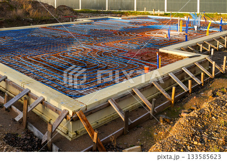 Underfloor heating system with pipes installed over rebar grid before concrete slab pouring 133585623