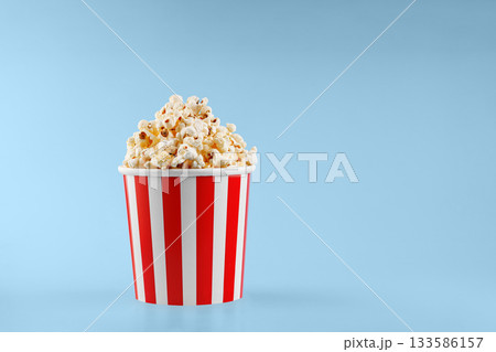 Classic red striped popcorn cardboard cup on blue background 133586157