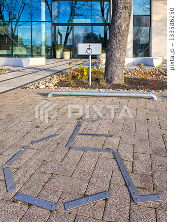 Accessible parking symbol and sign in front of modern glass building on a sunny day 133586250