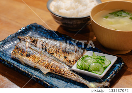 焼き秋刀魚ときゅうりの酢の物、ごはんと味噌汁を添えた和風の夕食 133587072