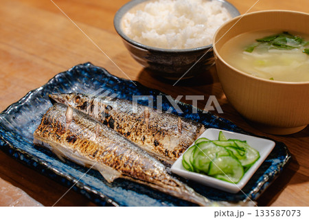 焼き秋刀魚ときゅうりの酢の物、ごはんと味噌汁を添えた和風の夕食 133587073