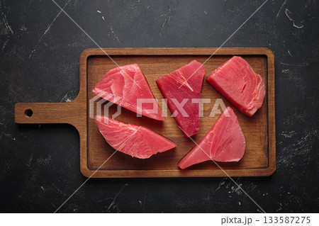 Raw tuna fish steaks fillet wooden cutting board black background healthy 133587275