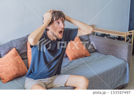 A man watching a football match on television at home, fully focused and relaxed in a cozy living room. Leisure time, sports entertainment, weekend relaxation and modern digital lifestyle concept 133587497