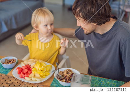A father having breakfast at the table with his young son in a bright home kitchen, sharing a warm morning moment. Family bonding, parenting, everyday routine and healthy lifestyle concept A father having breakfast at the table with his young son in a bright home kitchen, sharing a warm morning moment. Family bonding, parenting, everyday routine and healthy lifestyle concept 133587513
