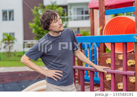 A man playing with his small son on a playground, laughing and engaging in active fun together in a bright outdoor setting. Family bonding, early childhood development and healthy outdoor lifestyle 133588191