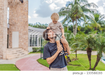 A man walking with his young son outdoors, holding hands and spending quality time together in a peaceful natural setting. Family bonding, parenting, childhood moments and healthy outdoor lifestyle 133588193