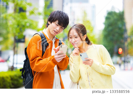 街中でスマホを見る若い男女 133588556