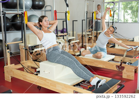 Young woman training her abs on pilates machine Young woman training her abs on pilates machine 133592262