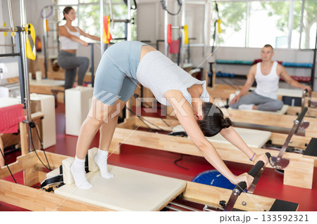 Young girl doing full body exercises lying on reformer device Young girl doing full body exercises lying on reformer device 133592321