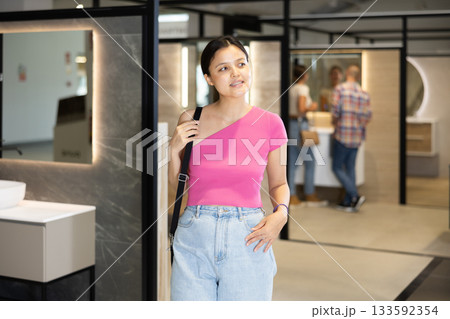Young Asian female shopper browsing bathroom fixtures in showroom 133592354