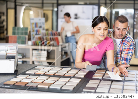 Couple browsing tile samples on display board in home improvement store Couple browsing tile samples on display board in home improvement store 133592447