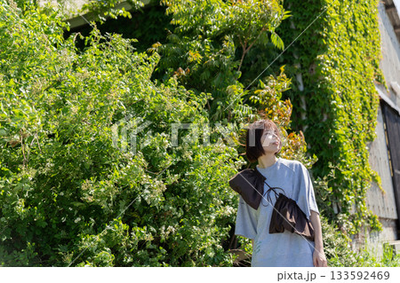 緑の塀の前で立つ女性 133592469