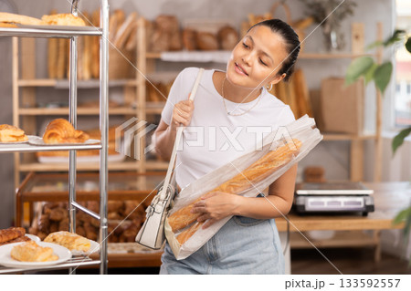 Asian woman holding a baguette in her hands 133592557