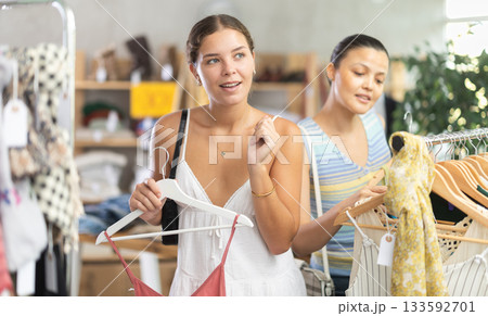 Girl customer choose something clothing for summer. Female client looking for clothes in background Girl customer choose something clothing for summer. Female client looking for clothes in background 133592701
