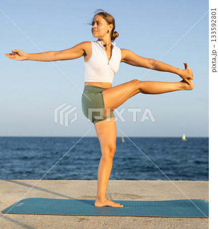 Athletic girl meditates in a yoga pose parshvottanasana on seashore Athletic girl meditates in a yoga pose parshvottanasana on seashore 133592801