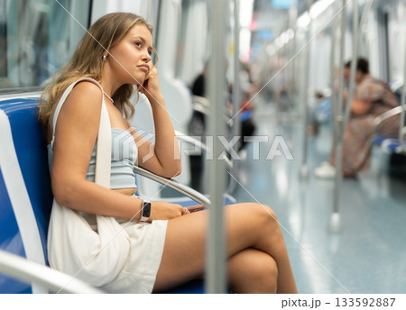 Young woman is sitting in subway car with phone, getting to work, school. Young woman is sitting in subway car with phone, getting to work, school. 133592887