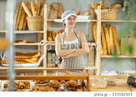Portrait of young positive female baker in uniform in bakery 133592955