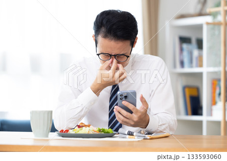 出勤前 スマホを見ながら食事をする男性 出勤前 スマホを見ながら食事をする男性 133593060