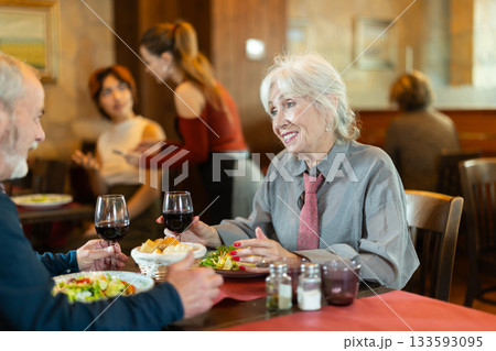 Elderly couple eating and talking in restaurant Elderly couple eating and talking in restaurant 133593095