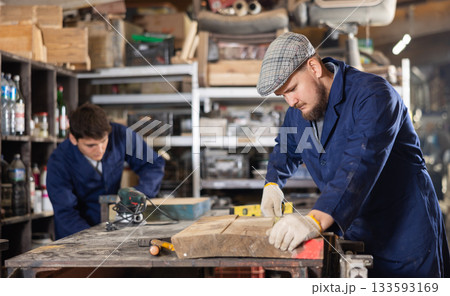 Young man measuring wooden board with tape measure Young man measuring wooden board with tape measure 133593169
