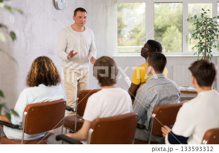Middle-aged man teacher reading lecture for a group of guys Middle-aged man teacher reading lecture for a group of guys 133593312