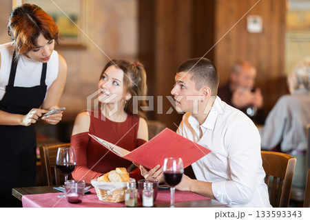 At cafe, Filipino girl waitress communicates with couple of customer, accepts order 133593343