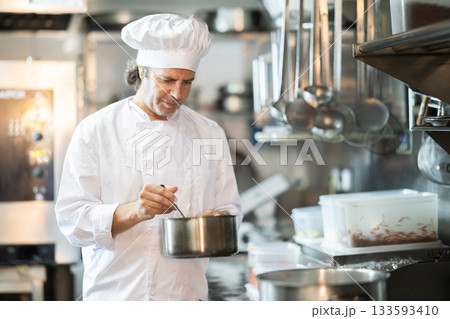 Man cook in kitchen is working near stove 133593410
