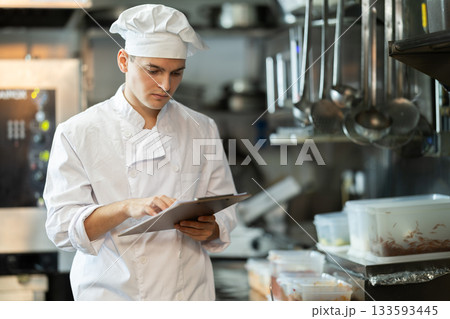 Young male chef conducts inspection in restaurant kitchen 133593445