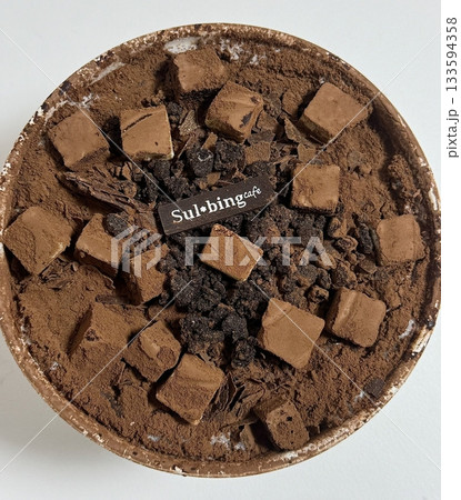 Rich and indulgent chocolate bingsu topped with chocolate syrup, brownie chunks, and chocolate shavings. A heavenly treat for chocoholics seeking a cool and creamy dessert escape. 133594358