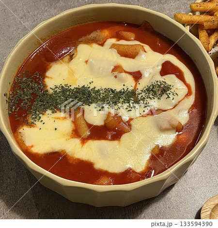 Spicy Korean tteokbokki with chewy rice cakes in a vibrant red sauce, topped with sesame seeds and green onions. A popular street food known for its addictive flavor and satisfying texture. 133594390