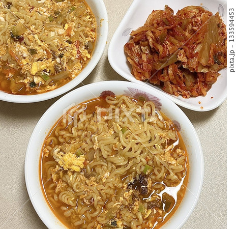 Steaming hot ramyun with rich, savory broth and chewy noodles, paired with spicy, tangy kimchi. A perfect Korean comfort food combination, balancing bold flavors and satisfying textures. 133594453