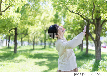 新緑の公園で腕でストレッチをする女性 新緑の公園で腕でストレッチをする女性 133595408
