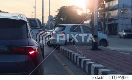 Rear side of car with turn on brake light. Waiting in line to make a U-turn in front. A blurry image of a white car making a U turn. Blurred of city and sunlight on the sky. Rear side of car with turn on brake light. Waiting in line to make a U-turn in front. A blurry image of a white car making a U turn. Blurred of city and sunlight on the sky. 133595929