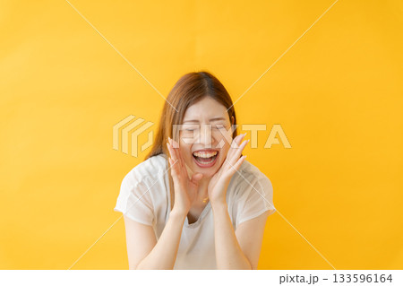 黄色い背景の前で応援する女性 133596164