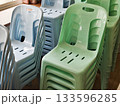 Stacked plastic chairs in pastel colors arranged for community or event use. 133596285