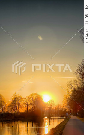 The breathtaking beauty of a stunning sunrise over serene, calm waters and lush trees 133596368