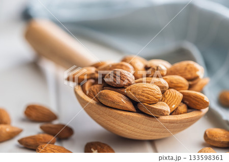Almond kernel nuts on wooden spoon on white table. Almond kernel nuts on wooden spoon on white table. 133598361