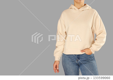 A person stands confidently wearing a casual hoodie and jeans A person stands confidently wearing a casual hoodie and jeans 133599060