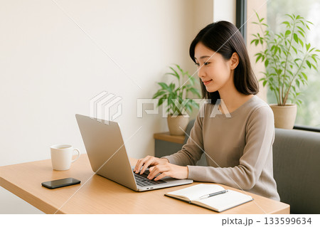 カフェでノートパソコンを使ってブログ執筆・SNS運用をする若い日本人女性のビジネスイメージ 133599634