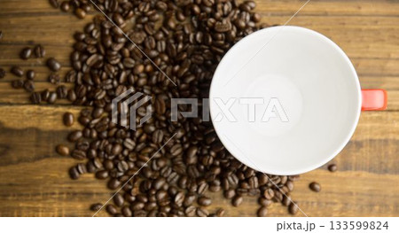 Flat design is showing dark roasted beans and red-handled white coffee cup resting on wood tabletop Flat design is showing dark roasted beans and red-handled white coffee cup resting on wood tabletop 133599824