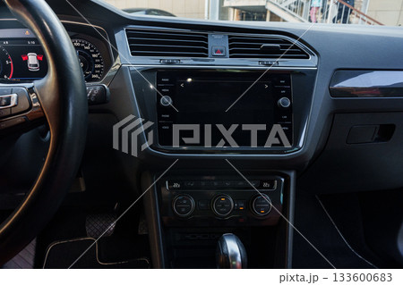 Modern car interior features dashboard display and control buttons situated in urban setting 133600683