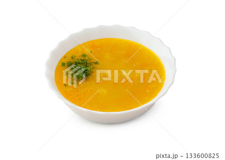 Yellow lentil soup topped with fresh herbs in a white bowl 133600825