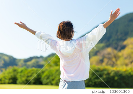 屋外でストレッチ体操をするミドル女性 屋外でストレッチ体操をするミドル女性 133601300