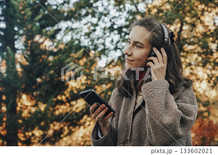 Young Woman Enjoying Music in Park During Autumn 133602021
