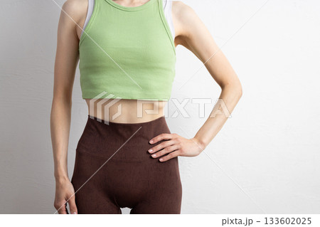 スポーツウェアを着た女性の引き締まった腹部のクローズアップ 133602025