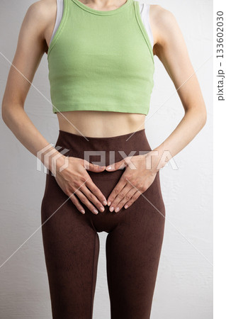 骨盤の位置を示すスポーツウェア姿の女性のクローズアップ 133602030