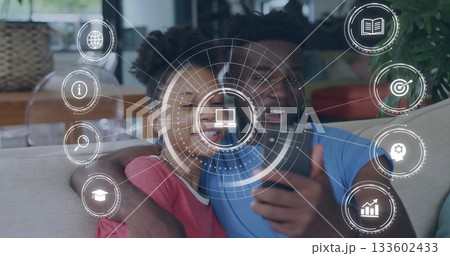 Smiling couple taking selfie in home living room, with smartphone and digital icons 133602433