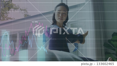 Stretching Korean woman in navy leggings, grey top on mat by window, floating financial graphs 133602465