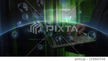 Typing mature Korean man holding laptop computer in high-tech environment, with green data overlays 133602556