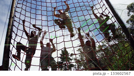 Climbing soldiers in camouflage pants pulling red rope cargo net at forest drill, showing teamwork Climbing soldiers in camouflage pants pulling red rope cargo net at forest drill, showing teamwork 133602567